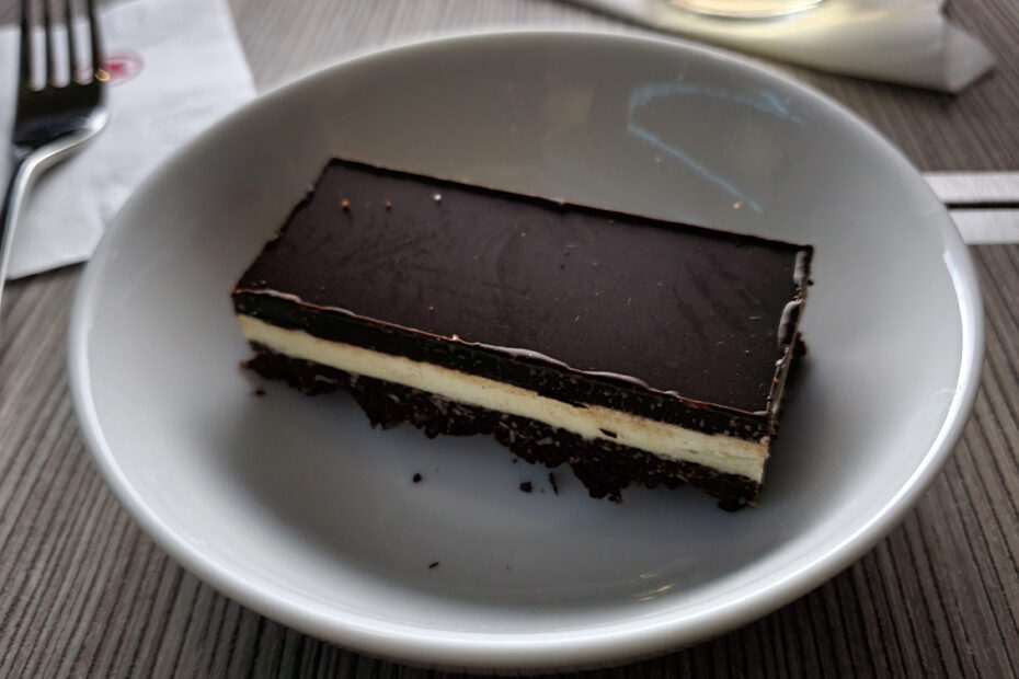A Nanaimo bar on a plate on an airplane fold out table.