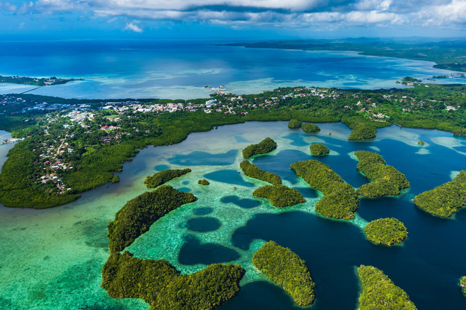 Koror, Palau as seen from above, surrounded by reefs and tiny, lush, green islands like candy drops in the Pacific Ocean.