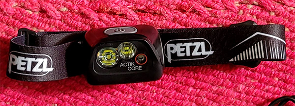 The Petzl Actik Core Rechargeable headlamp sitting on a red carpet