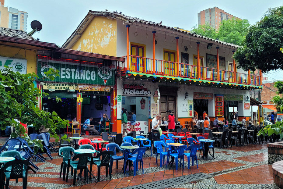 Colorfully painted restaurants with blue and red plastic tables sitting outside in the main square of Sabaneta, my favorite neighborhood for digital nomads in Medellin, Colombia