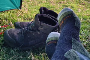 Tough wool boot cushion sock, resting after a day of hiking, beside a pair of Inov-8 Roclite Pro G 400 waterproof vegan hiking boots, on grass