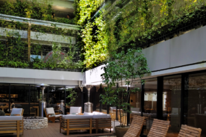 The inner atrium of the Good Nature Hotel, Kyoto, one of the hotels you can get discounts on by booking with Agoda. The atrium has wood loungers around and sofas below open corridors covered with a curtains of green plants and then sunshine streaming down on them.