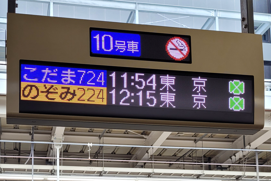 Digital sign at Shin-Osaka Station. The sign lists the next Kodama and Nozomi Shinkansen trains bound for Tokyo and indicates that this car is a non-smoking Green Car